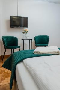 a bed with two green chairs and a tv at Zajazd Błonie in Błonie