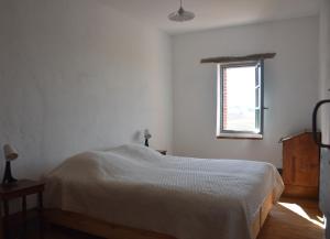 a white bedroom with a bed and a window at Maison ou chambres dans une belle ferme lauragaise 