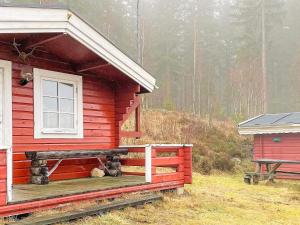 a red cabin with a window and a teddy bear on the porch at Holiday home SEXDREGA in Sexdrega