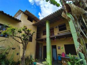 une maison jaune avec un arbre devant elle dans l'établissement Pousada Flamboyan, à Rio de Contas