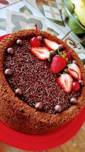 a chocolate cake with strawberries on top on a red plate at Pousada Flats Alegria in Olímpia