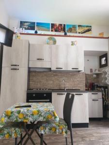 una cucina con armadi bianchi, tavolo e lavandino di La casa di Adina a Agrigento