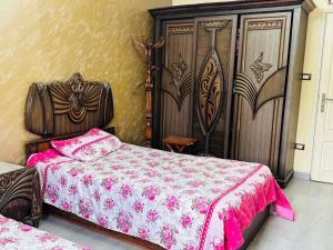 Schlafzimmer mit einem Bett mit rosa Tagesdecke in der Unterkunft 100برج الثورة الدور 2 in Kairo