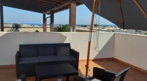 un divano nero su un balcone con ombrellone di Casa Serena a San Vito lo Capo