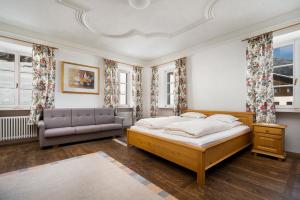 ein Schlafzimmer mit einem Bett, einem Sofa und Fenstern in der Unterkunft Gasthof Sillianer Wirt in Sillian