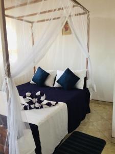 - une chambre dotée d'un lit à baldaquin avec des oreillers bleus et blancs dans l'établissement Sun and Sand Apartment, à Ahangama