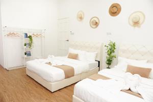 2 camas en una habitación con paredes blancas en OHHSEM Hotel, en Semporna