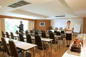 a woman standing in a room with tables and chairs at Bansabai Hostelling International in Bangkok