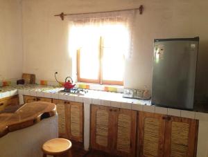 a kitchen with a refrigerator and a table and a window at Rancho Quitapenas Bungalows in San Pedro de Atacama