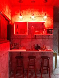 een rode keuken met een aanrecht en 2 krukken bij Casa ampla com Wi-Fi e garagem para dois veículos in Campos dos Goytacazes