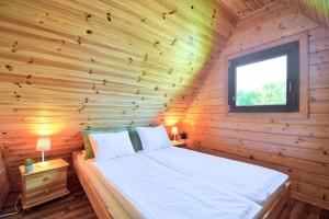 Bett in einem Holzzimmer mit Fenster in der Unterkunft Houses with a garden- Domki z ogródkiem Radison domki in Mielno