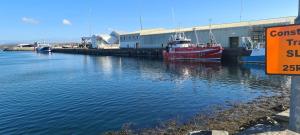 a red boat is docked next to a building in the water at An Chéibh B&B in Rossaveel