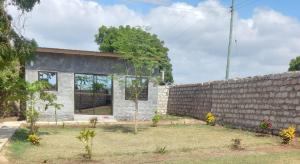 a house with a brick wall next to a yard at BreezHub Residence in Kikambala