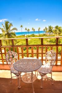 una mesa y sillas en un balcón con vistas a la playa en Villaggio Orizzonte, en Salvador
