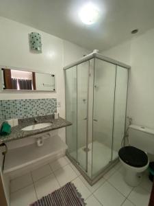 y baño con ducha de cristal y aseo. en Resort Villa da praia apto 30 arraial do cabo en Arraial do Cabo