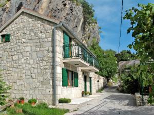 a stone building with green doors and a balcony at House Podaspilje Omis in Podšpilje