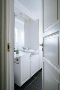 La salle de bains blanche est pourvue d'un lavabo et d'un miroir. dans l'établissement Ocean Views and Gorgeous Design in a Light-Filled 3 BDRM/1.5 Bath Village Home, à Stokkseyri