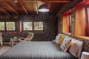 una camera da letto con un letto e un muro di pietra di Papaya Cottage Punta del Hidalgo La Azócar a Punta del Hidalgo