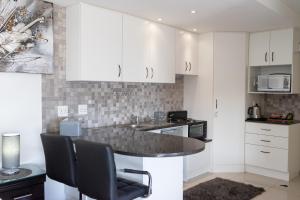 a kitchen with white cabinets and a counter top at Bar-t-nique Guest House in Mossel Bay