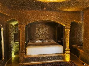 a bedroom with a bed in a gold room at Cappadocia Empire Cave Hotel in Goreme