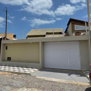a garage with two white garage doors in front of a house at Casa de Praia do Luiz in Luis Correia