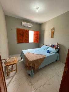 a bedroom with a bed with blue sheets and a window at Casa de Praia do Luiz in Luis Correia