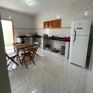 a kitchen with a table and a white refrigerator at Casa de Praia do Luiz in Luis Correia