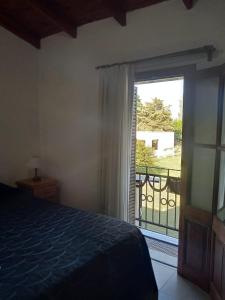 1 dormitorio con 1 cama y puerta a un balcón en El Quincho en Gualeguay