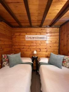 2 Betten in einem Zimmer mit Holzwänden in der Unterkunft Xalet de Cal Fera in La Coma i la Pedra