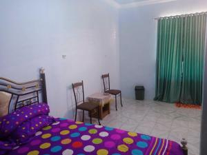 um quarto com uma cama e cadeiras e uma cortina verde em EXPRESS O 92251 Jaya Kusuma Homestay em Jambi