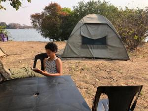 a young boy laying on a table in front of a tent at Nahubwe Safari Lodge in Ngoma