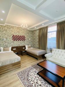 1 Schlafzimmer mit 2 Betten, einem Sofa und einem Tisch in der Unterkunft KOCHEVNIK NOMAD hotel in Bischkek