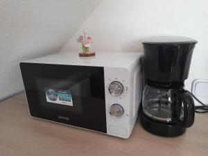 - un four micro-ondes assis sur un comptoir à côté d'une cafetière dans l'établissement Apartma Lena, à Kranjska Gora