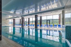 une grande piscine avec des chaises bleues dans un bâtiment dans l'établissement Elena Spa Resort, à Bukovel