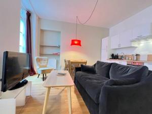 uma sala de estar com um sofá, uma televisão e uma mesa em Charmant T3 - Cœur de Cauterets em Cauterets