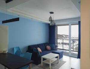 a living room with a blue couch and a table at Apartament z widokiem na panoramę Gdyni w Modern Tower ATAL in Gdynia