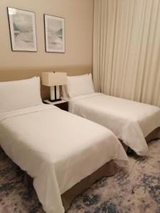 two beds in a hotel room with white sheets at Two Bedrooms Apartment at Address Residence Fujairah in Sharm
