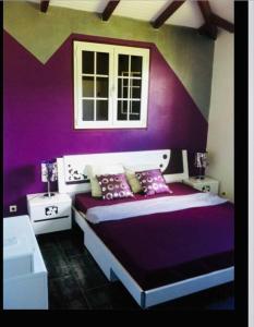 een paarse slaapkamer met een bed en een raam bij Villa Caraibes in Petit-Canal