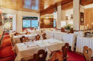 un restaurant avec des tables, des chaises et des nappes blanches dans l'établissement Hotel Mirage, à Cortina dʼAmpezzo