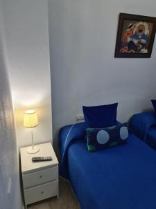 een slaapkamer met een blauw bed en een nachtkastje bij apartamento céntrico jerez calle tucan n17 in Jerez de la Frontera