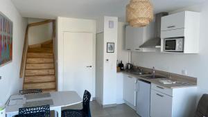 a kitchen with white cabinets and a table with chairs at Résidence l’Esprit de la mer in Combrit +29 photos