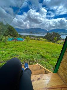 una persona tumbada en un porche mirando a un campo en Refugio del Neusa, en Cogua