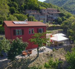 a red house with a table and a tent at Agriturismo LA VECCHIA CASCINA in Filattiera