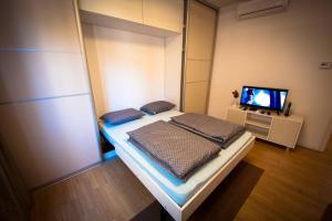 ein kleines Schlafzimmer mit einem Bett und einem TV in der Unterkunft Apartman Omega in Sarajevo