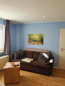 a living room with a brown couch and a blue wall at City - Appartement in Lengerich