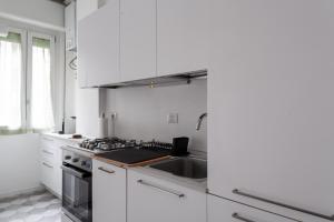 - une cuisine blanche avec évier et cuisinière dans l'établissement BnButler - Casa Lario - Isola District, à Milan