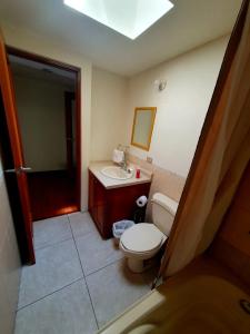 a bathroom with a toilet and a sink and a mirror at Apartamento Aeropuerto La Aurora Guatemala in Guatemala