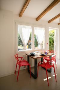 una sala da pranzo con sedie rosse, tavolo e finestre di Giardino in laguna a Murano