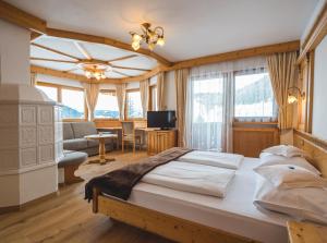 a bedroom with a large bed and a living room at Garni Hotel Rosengarten B&B in Selva di Val Gardena