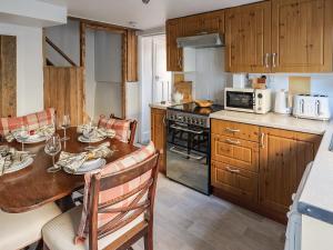 The Saddlers Cottage في East Boldon: مطبخ مع طاولة خشبية وغرفة طعام